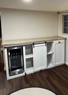 an empty kitchen with white cabinets and wood floors