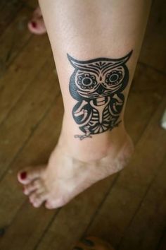 an owl tattoo on the leg of a woman