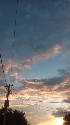 the sun is setting behind power lines and telephone poles