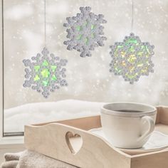 two snowflakes hanging from the ceiling next to a coffee cup on a tray