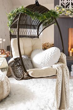 a hanging chair in front of a fireplace with pillows and blankets on the bottom shelf