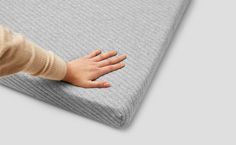 a child's hand is on the edge of a mattress