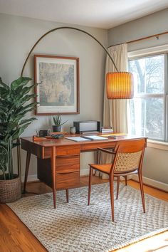 a desk with a lamp, chair and rug in front of a window on the floor