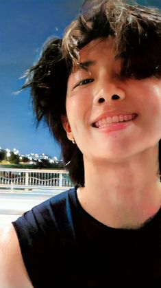 a woman with short hair smiling and looking up at the sky in front of a white fence