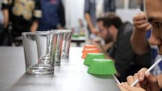 a man is brushing his teeth while sitting at a table with other people in the background