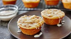 two muffins on a plate with icing drizzled around them