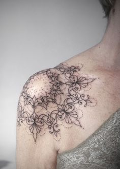 a woman's shoulder with an intricate tattoo design on her left arm and chest