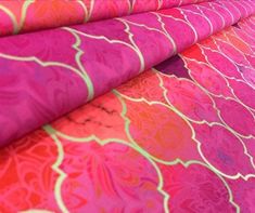 pink and orange fabric with an intricate design on it's edges, folded in rows