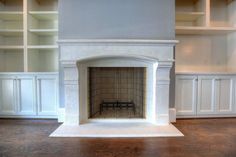 an empty room with a fireplace and built - in shelving