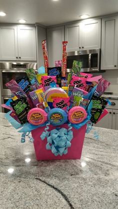 a pink basket filled with candy and candies on top of a kitchen countertop