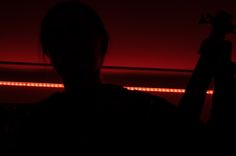 the silhouette of a person holding a camera in front of a red light