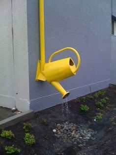 a yellow watering hose attached to the side of a building with water coming out of it