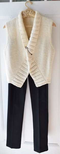 a white sweater and black pants hanging on a door handle with an open jacket over it