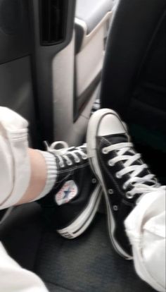 someone is wearing black and white converse shoes in the car with their feet propped up