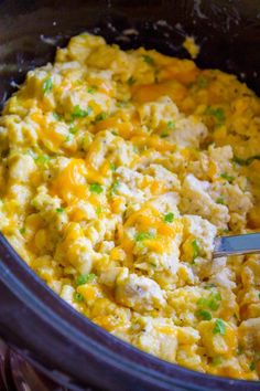 a crock pot filled with scrambled eggs and green onions