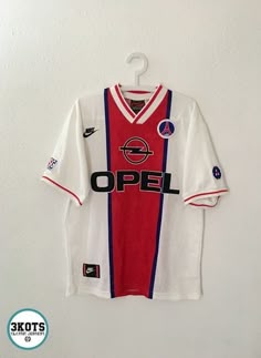a soccer jersey hanging on the wall in front of a white wall with an open sign
