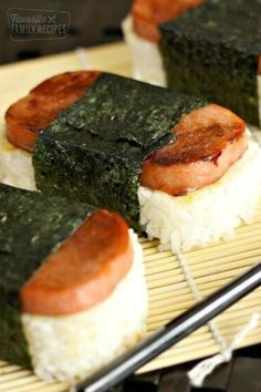 some sushi is sitting on a bamboo mat with chopsticks next to it