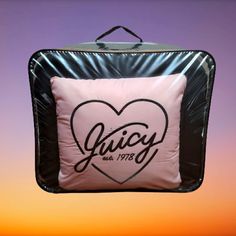 a pink and black square pillow with the word juicy on it hanging from a hook