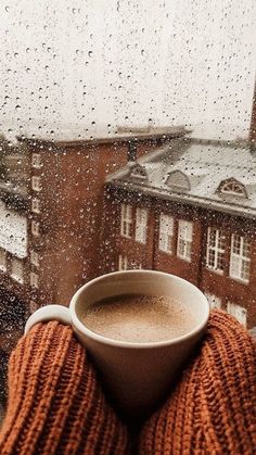 a cup of coffee sitting on top of a window sill next to a building