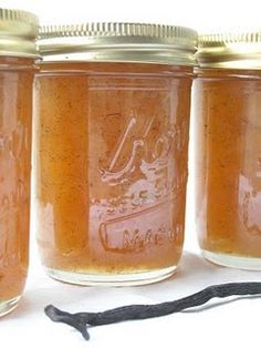 four jars filled with orange liquid next to a black string on a white tablecloth