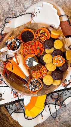 a wooden platter filled with halloween desserts and candies on top of a table