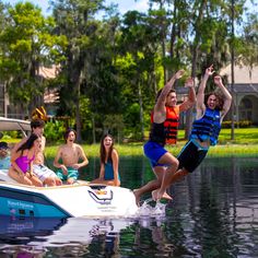 two people jumping into the water from a speedboat in front of several other people