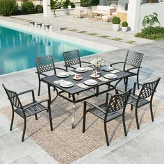 an outdoor dining table with six chairs and plates on it near a swimming pool area