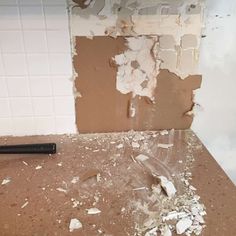 a bathroom that has been torn apart and the floor is littered with debris, including a hammer