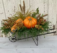 a wheelbarrow filled with pumpkins and greenery