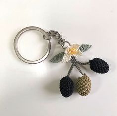 a crocheted pine cone keychain with flowers and leaves hanging from it