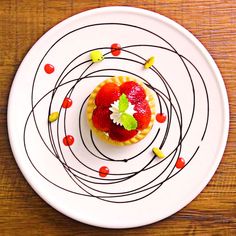 a small dessert on a white plate with chocolate sauce and fruit garnishes