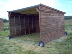 a small wooden shed sitting on top of a grass covered field