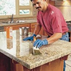 a man with blue gloves on is cleaning a granite counter top