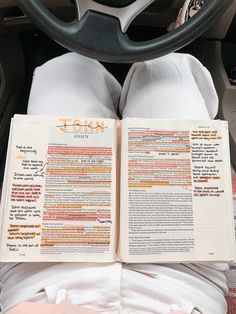 a person reading a book while sitting in a car with their feet on the steering wheel