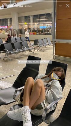 a woman sitting in an airport waiting for her luggage