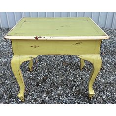 an old yellow desk sitting on top of gravel