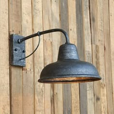 an industrial style wall light mounted on a wooden wall next to a wood paneled fence