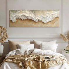 a large painting on the wall above a bed in a room with pillows and blankets