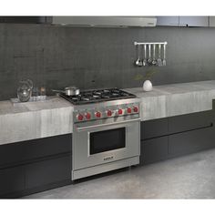 a stove top oven sitting inside of a kitchen next to a counter with pots and pans on it