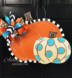 a door hanger decorated with an orange pumpkin and polka dot bow on the front