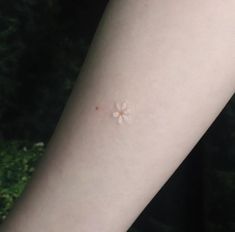 a person with a small flower tattoo on their arm