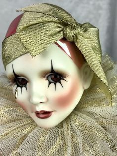 a close up of a doll's face wearing a gold tutu and headband