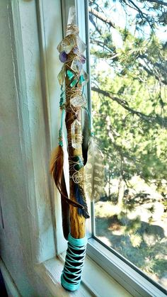 a window sill with a wind chime hanging from it's side next to a tree