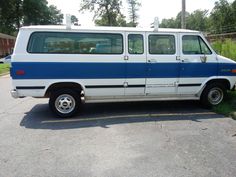 an old white and blue van parked in a parking lot