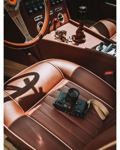 a camera sitting on top of a brown leather seat next to a car steering wheel