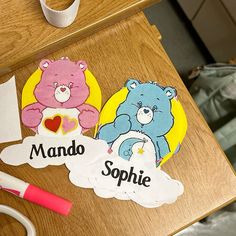 there are two teddy bears on the table with name tags and scissors next to them