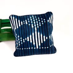 a blue and white pillow sitting on top of a wooden bench next to a green chair