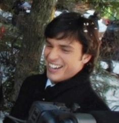 a man is smiling while holding a camera