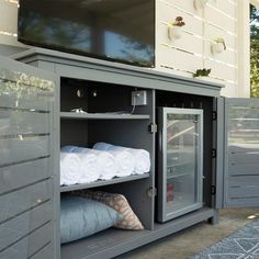 an outdoor entertainment center with towels on the shelves and a television mounted to the wall