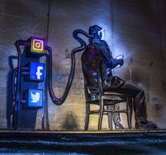 a man sitting on a chair in front of a wall with a phone and an octopus painted on it